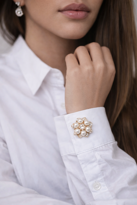 Close-up of a person wearing a white shirt with a decorative cuff pin.