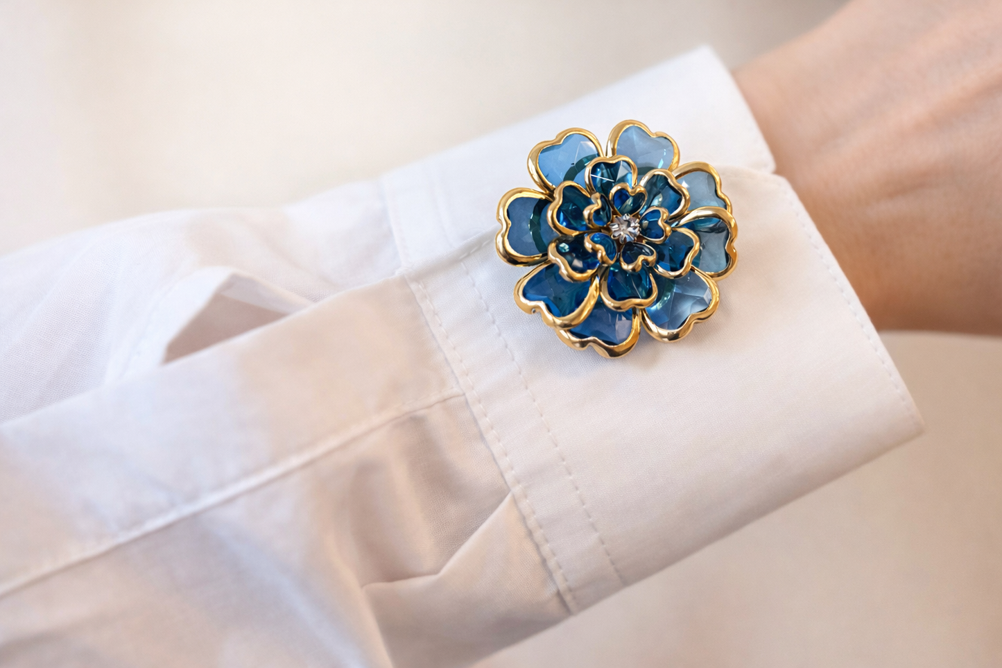 Blue floral brooch on a white shirt cuff