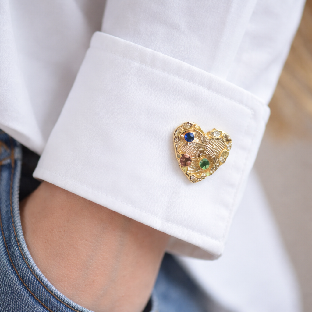 Heart-shaped cufflink with gemstones on a white shirt cuff