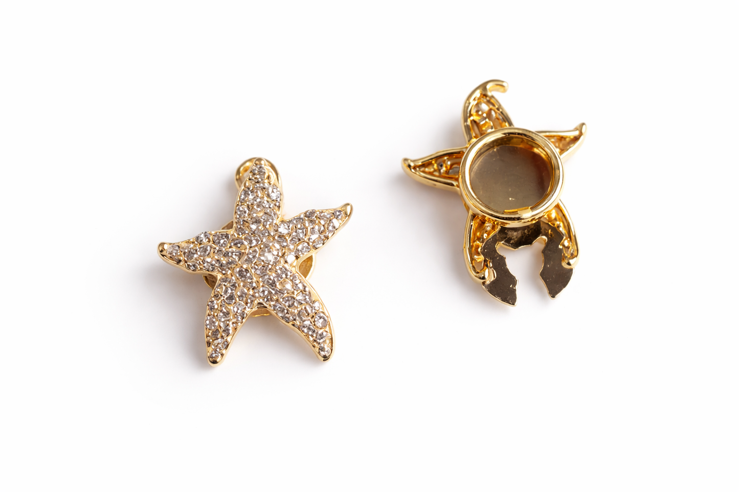 Two star-shaped gold jewelry pieces on a white background